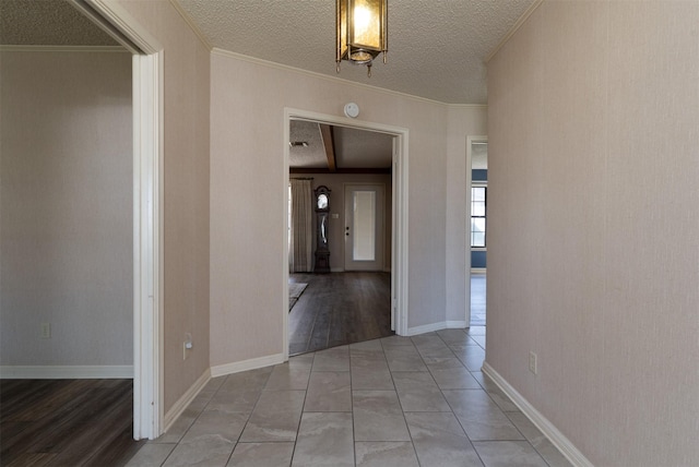 hall featuring light tile patterned floors, baseboards, a textured ceiling, crown molding, and beamed ceiling