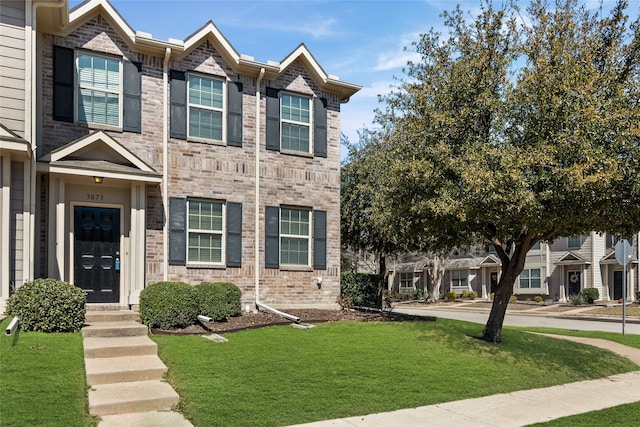 multi unit property with brick siding and a front lawn