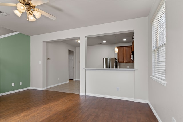 unfurnished living room with visible vents, a healthy amount of sunlight, ceiling fan, and wood-type flooring