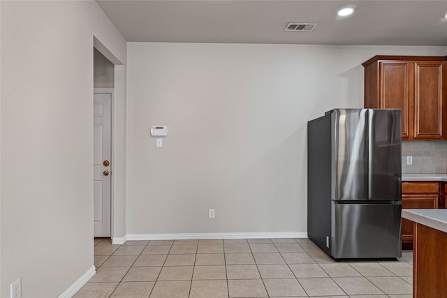 kitchen featuring light tile patterned floors, visible vents, light countertops, and freestanding refrigerator