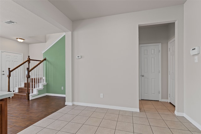 spare room with light tile patterned floors, visible vents, baseboards, and stairway