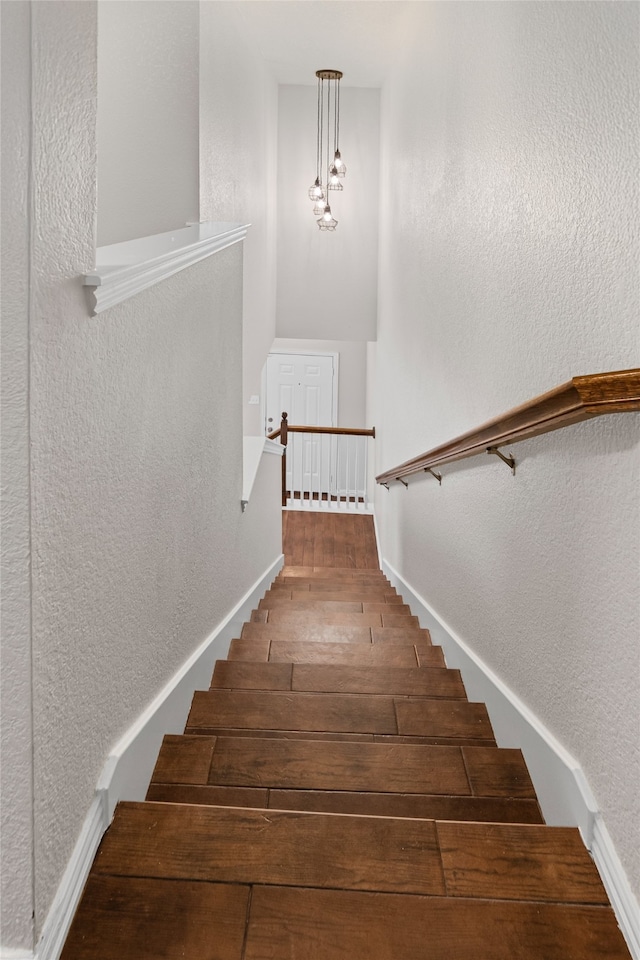 staircase with hardwood / wood-style floors and a textured wall