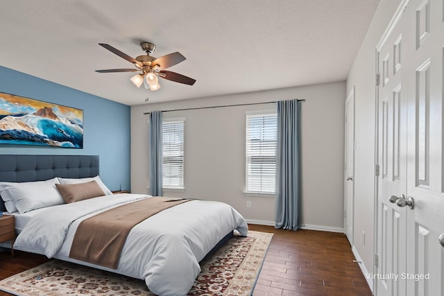 bedroom with dark wood-style floors, baseboards, a closet, and ceiling fan