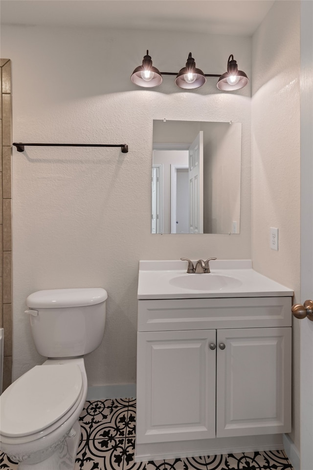 bathroom with baseboards, toilet, and vanity