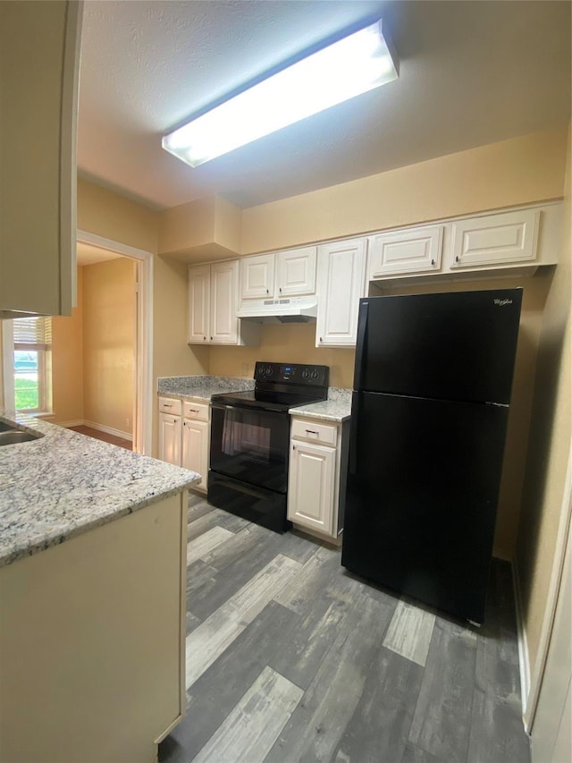 kitchen featuring under cabinet range hood, light wood-style floors, black appliances, and white cabinets