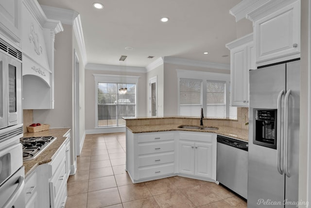 kitchen with a peninsula, ornamental molding, a sink, white cabinets, and appliances with stainless steel finishes