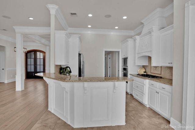 kitchen featuring visible vents, backsplash, light stone countertops, a peninsula, and ornate columns