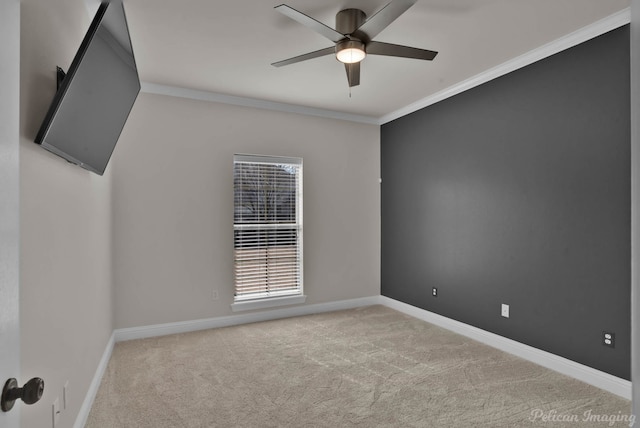 spare room with crown molding, light colored carpet, baseboards, and ceiling fan