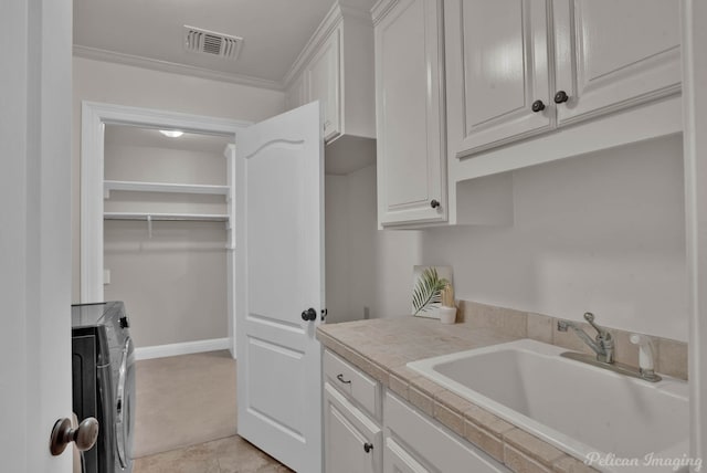 laundry room featuring visible vents, a sink, crown molding, cabinet space, and separate washer and dryer