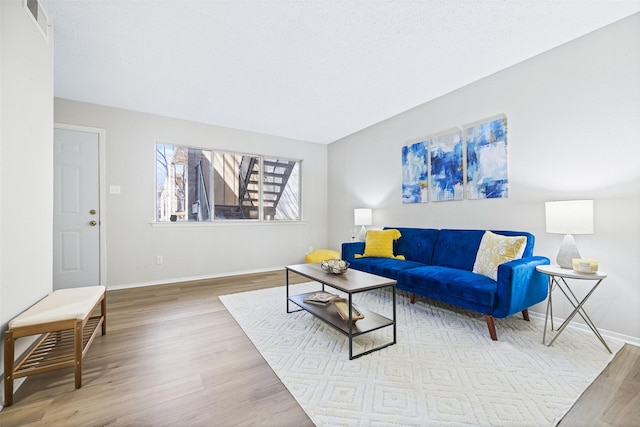 living area featuring visible vents, wood finished floors, and baseboards