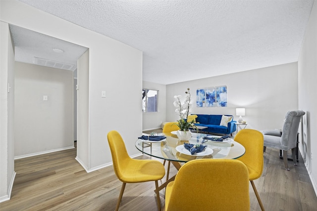 5831 Harvest Hill Rd Unit 1069, Dallas, TX 75230 - dining room featuring wood finished floors, baseboards, and a textured ceiling