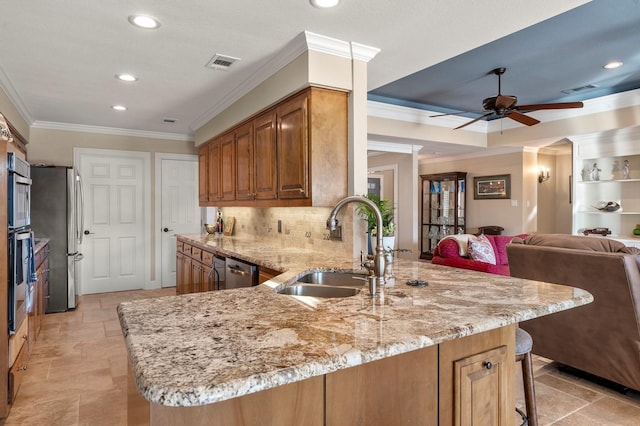 kitchen with light stone countertops, visible vents, a peninsula, a sink, and appliances with stainless steel finishes