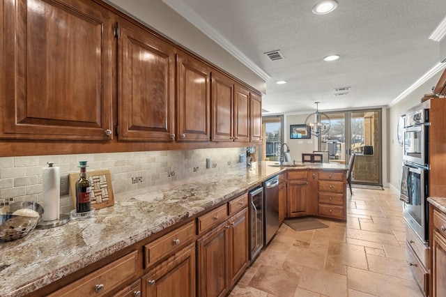 kitchen with stone tile floors, a peninsula, a sink, ornamental molding, and appliances with stainless steel finishes