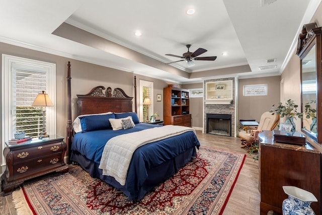 bedroom featuring a tray ceiling, multiple windows, and ornamental molding