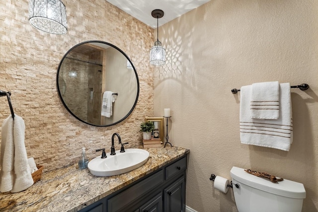 bathroom with toilet, vanity, and a textured wall