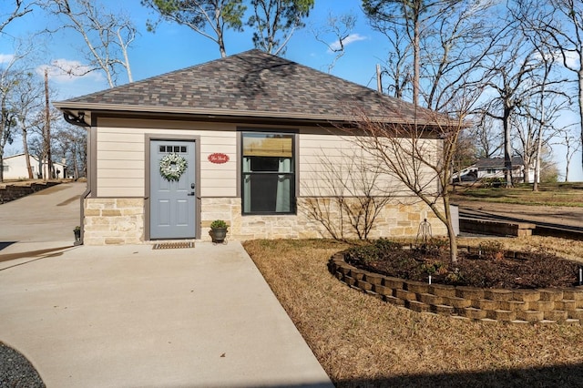 exterior space with stone siding and a shingled roof