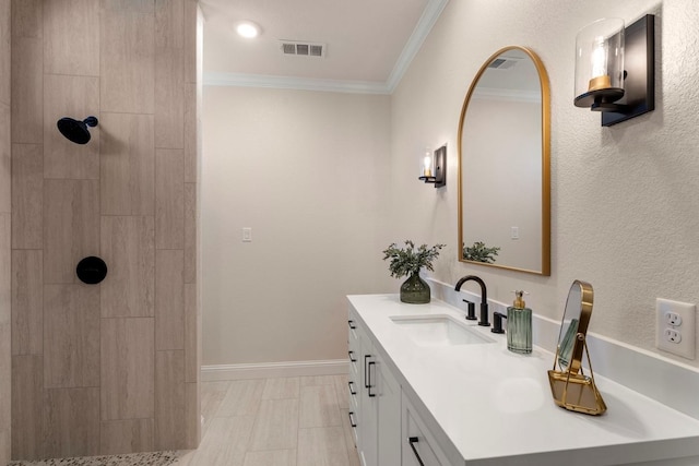 full bathroom featuring a tile shower, visible vents, vanity, and crown molding