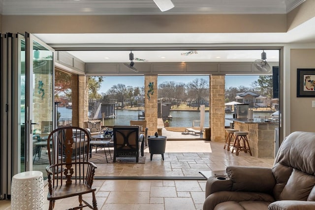 living room with crown molding, a water view, and stone tile flooring