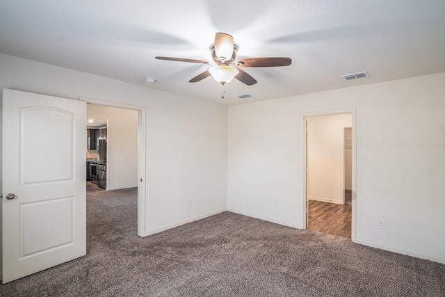 carpeted spare room featuring visible vents, baseboards, and ceiling fan