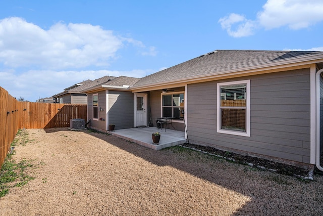 back of house featuring a shingled roof, ceiling fan, central air condition unit, a fenced backyard, and a patio area