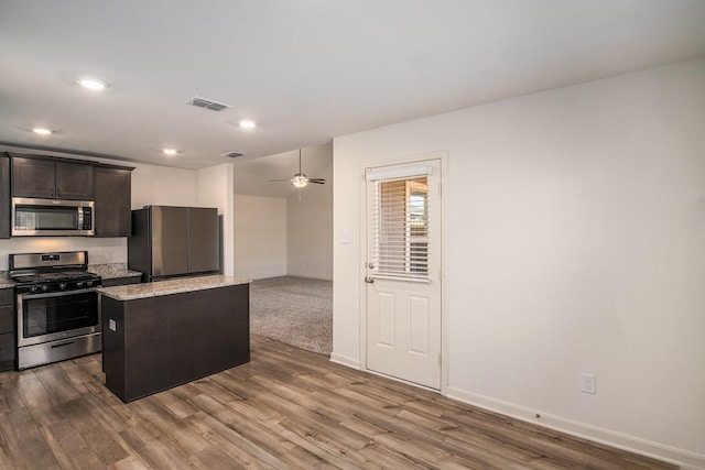 kitchen featuring visible vents, a center island, baseboards, appliances with stainless steel finishes, and dark wood-style flooring