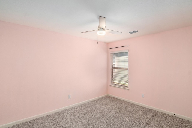 carpeted spare room featuring baseboards, visible vents, and ceiling fan