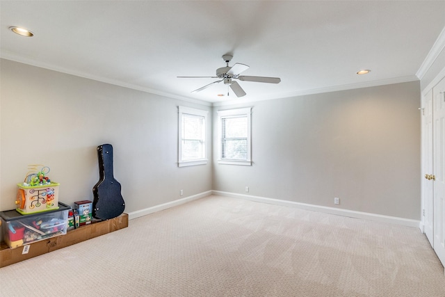 spare room with a ceiling fan, baseboards, light colored carpet, and crown molding