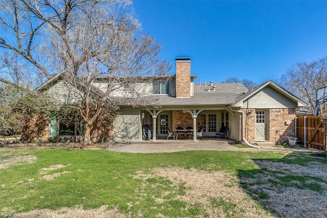 rear view of house with fence, a yard, a chimney, a patio area, and brick siding