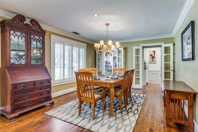 dining room featuring an inviting chandelier, wood finished floors, visible vents, and ornamental molding