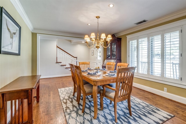 dining area featuring visible vents, stairway, ornamental molding, wood finished floors, and a notable chandelier