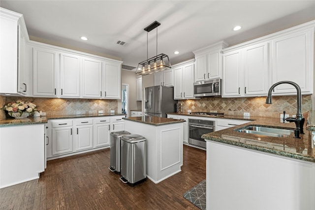 kitchen featuring visible vents, dark wood-style flooring, a sink, white cabinets, and appliances with stainless steel finishes