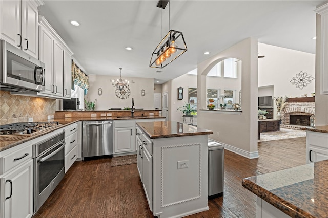 kitchen featuring a sink, a brick fireplace, appliances with stainless steel finishes, and a wealth of natural light