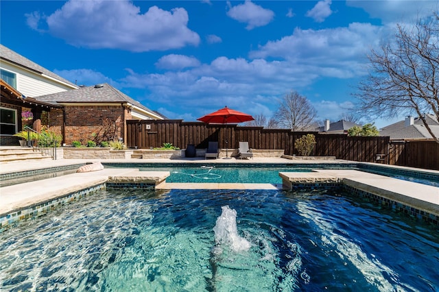 view of swimming pool featuring a pool with connected hot tub and a fenced backyard