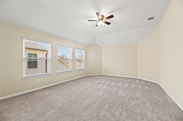 spare room with visible vents, carpet flooring, a ceiling fan, and vaulted ceiling