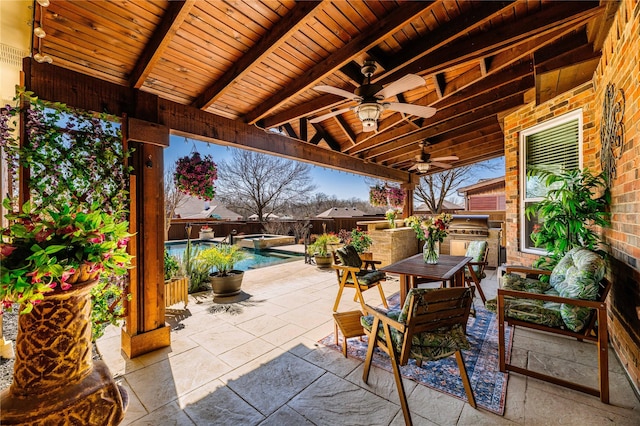 view of patio / terrace with an outdoor kitchen, outdoor dining space, a ceiling fan, and a pool with connected hot tub