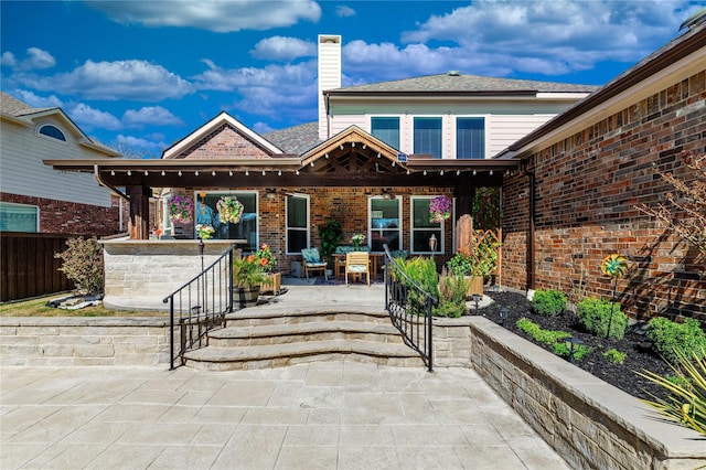 back of property with a patio, brick siding, a chimney, and fence