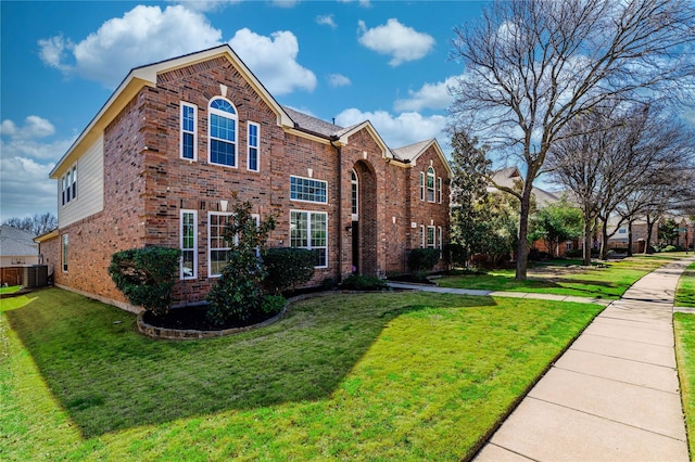 view of front facade with central air condition unit, brick siding, and a front lawn