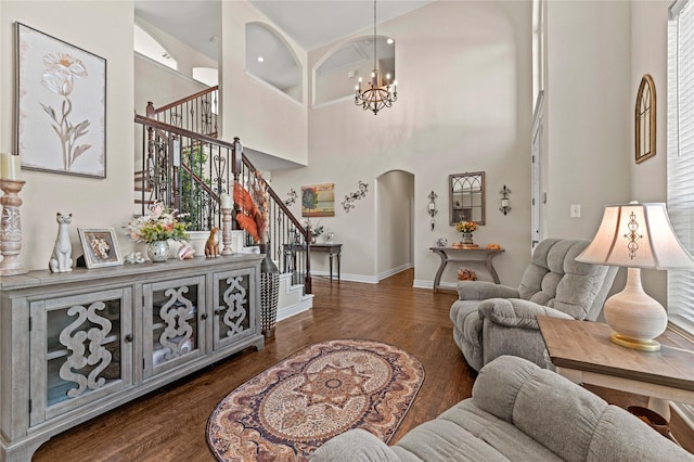 living area with stairway, arched walkways, dark wood-type flooring, and a chandelier