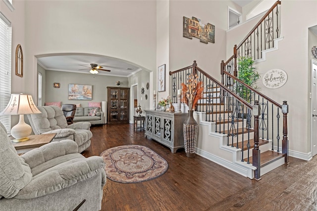 living area with baseboards, stairs, a high ceiling, wood finished floors, and arched walkways