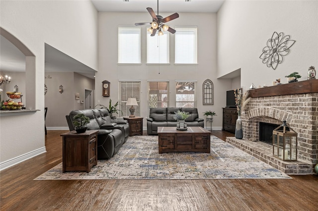 living area featuring a fireplace, wood finished floors, baseboards, and arched walkways