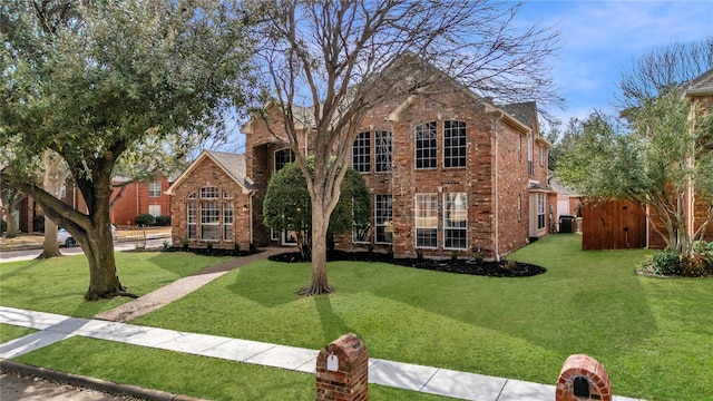 traditional home featuring a front yard and brick siding