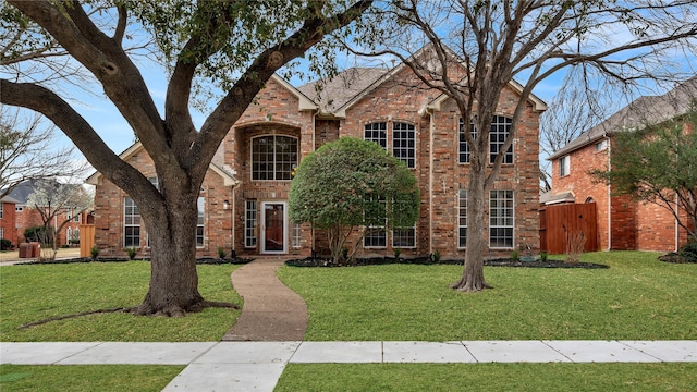 traditional-style house featuring a front lawn and brick siding