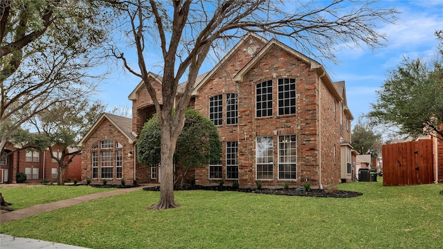 traditional-style home featuring a front lawn, central air condition unit, fence, and brick siding