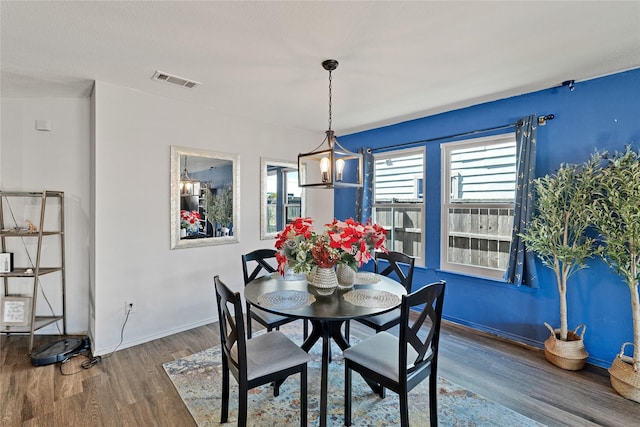 dining space featuring an inviting chandelier, wood finished floors, visible vents, and baseboards