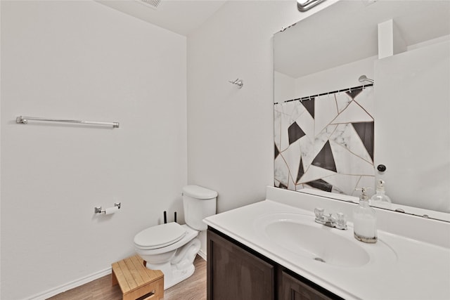 bathroom with baseboards, toilet, wood finished floors, and vanity