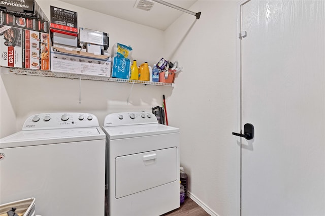 washroom featuring wood finished floors, baseboards, visible vents, washing machine and clothes dryer, and laundry area