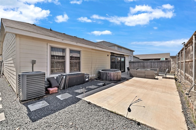 rear view of house featuring a patio area, central air condition unit, a hot tub, and a fenced backyard