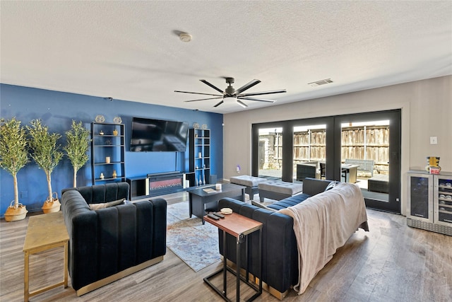 living room with wood finished floors, french doors, visible vents, and a textured ceiling