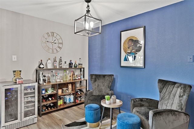 sitting room featuring wood finished floors, a dry bar, beverage cooler, and a chandelier