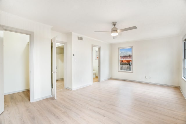 unfurnished bedroom featuring a spacious closet, visible vents, light wood finished floors, ensuite bathroom, and a closet